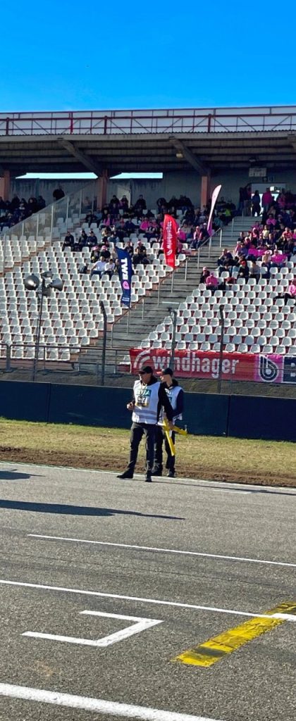 Helfer auf der Strecke vor der vollbesetzten Tribüne