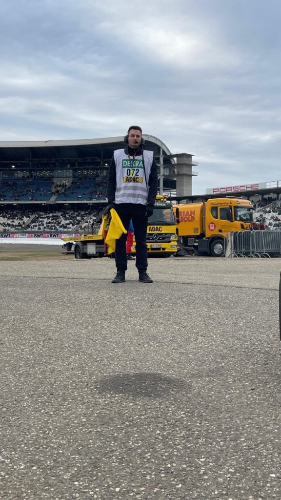 Helfer mit gelber Flagge vor Tribüne und Abschleppwagen