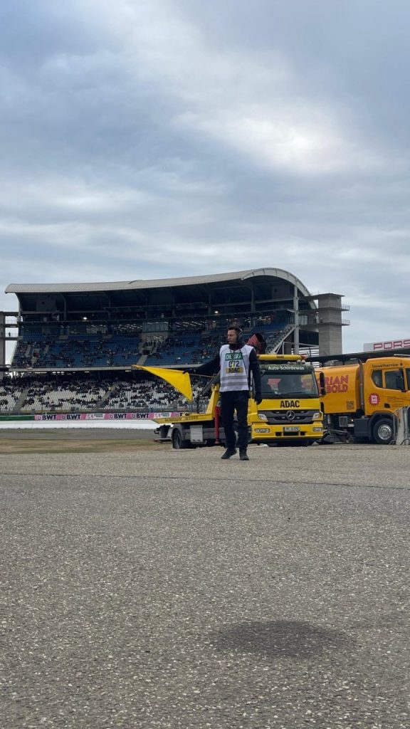 Helfer mit Flagge vor Abschleppwagen und Tribüne